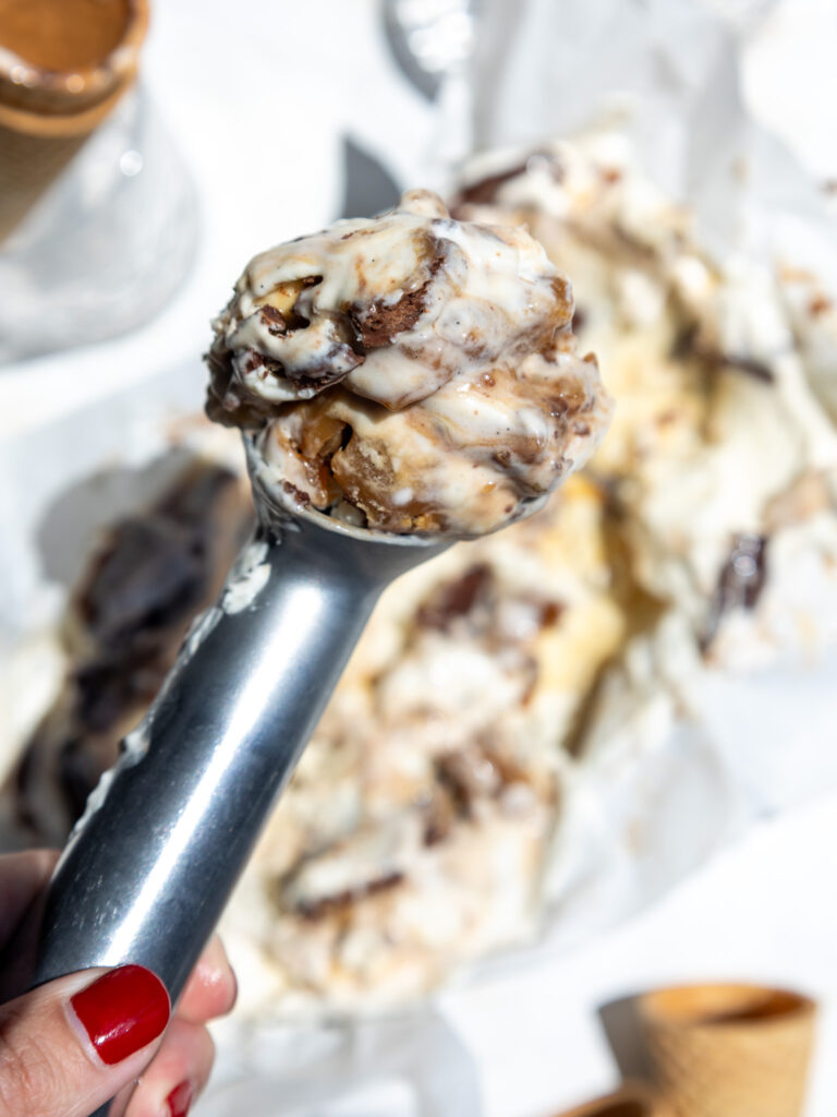 image of a scoop of chocolate caramel ice cream being held up in the sun