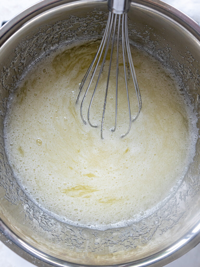 image of egg whites and sugar being mixed together over a double boiler to make swiss meringue buttercream frosting