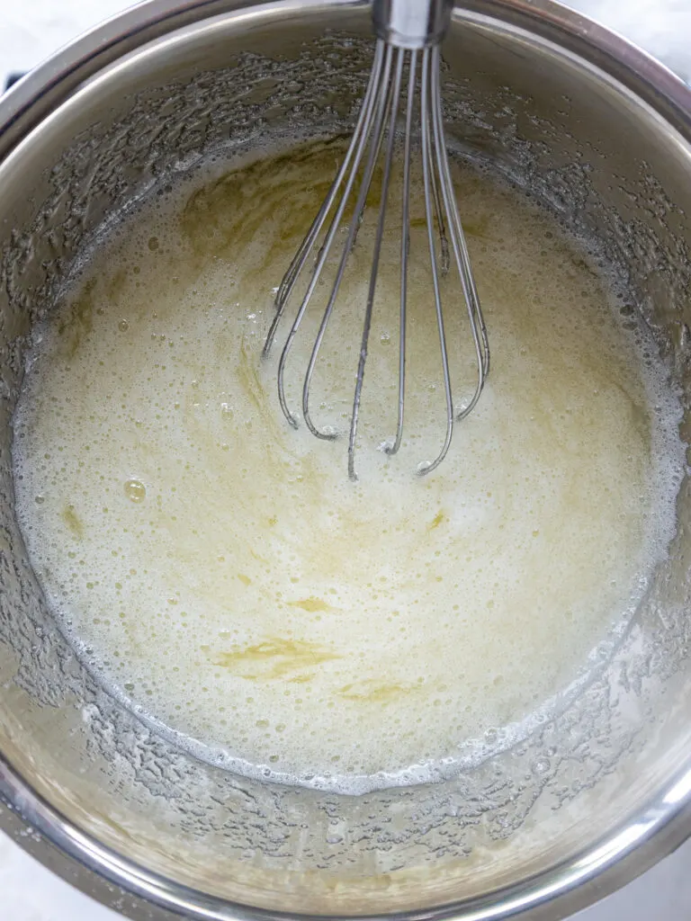 image of egg whites and sugar being mixed together over a double boiler to make swiss meringue buttercream frosting