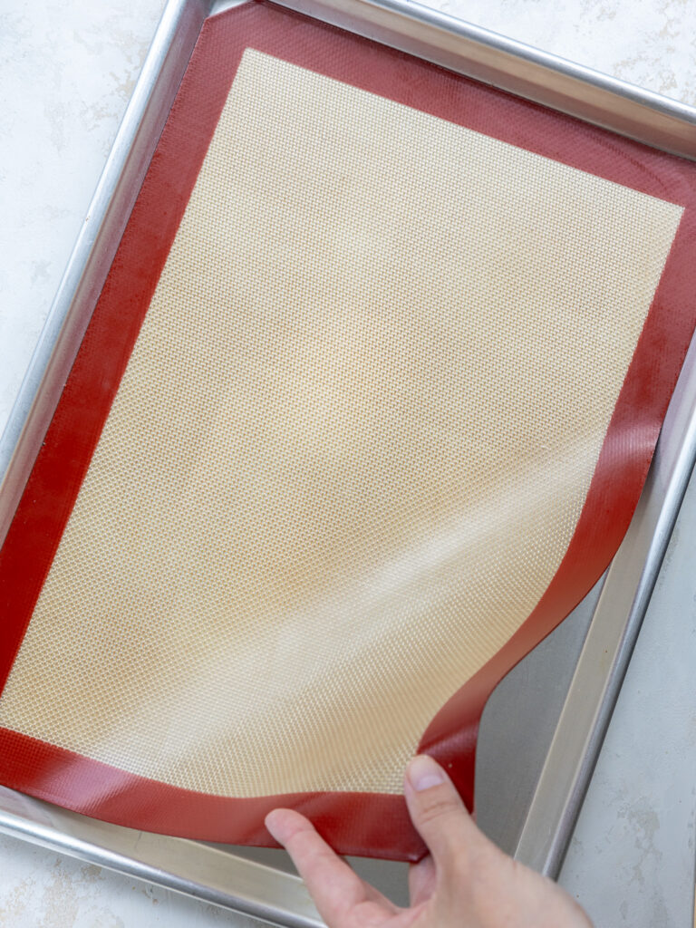 image of a baking sheet being lined with a silicone mat