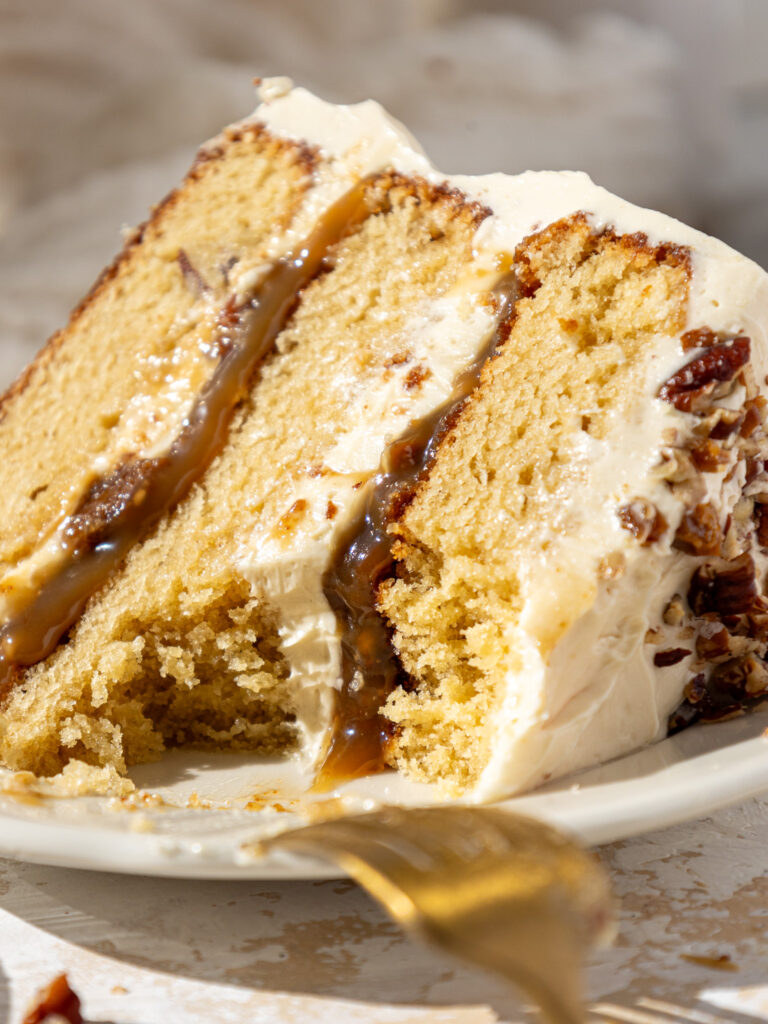 image of a slice of butterscotch toffee cake on a plate that's been cut into to show it's delicious filling