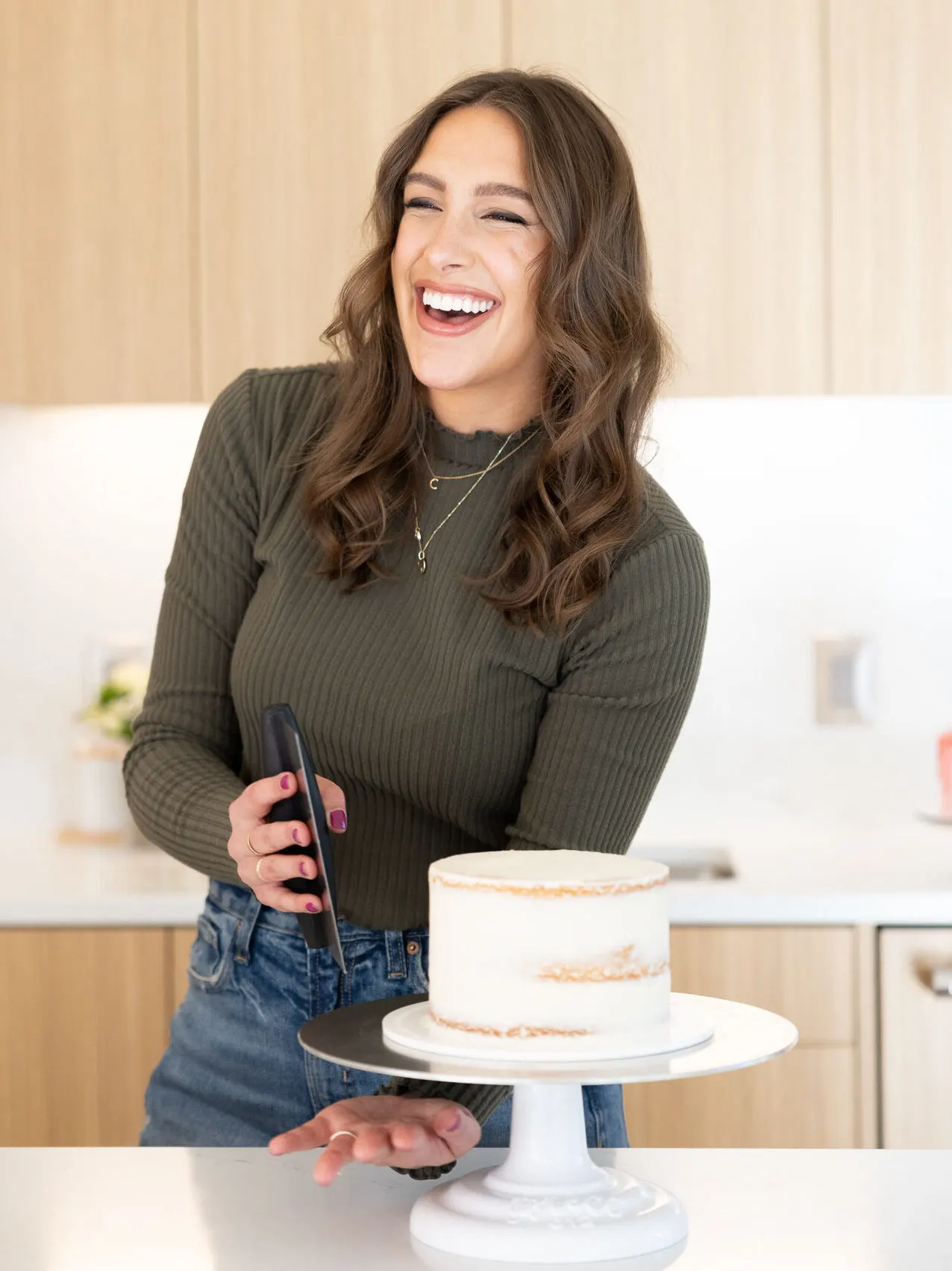 image of chelsey white of chelsweets crumb coating a cake with a bench scraper