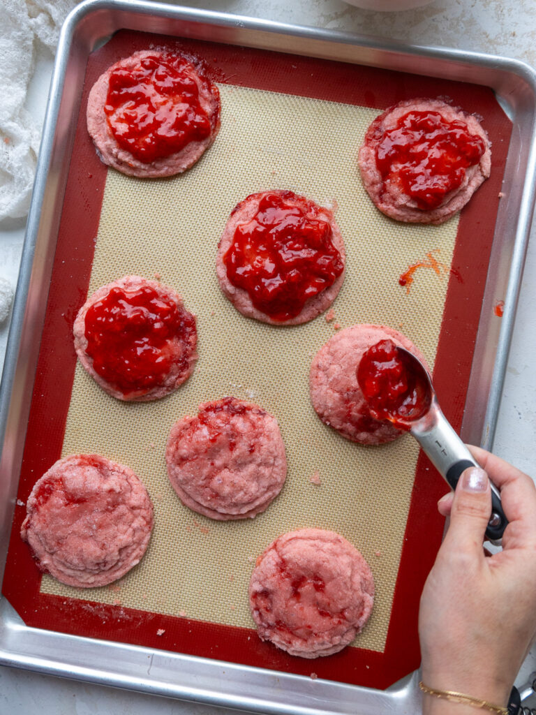 image of strawberry reduction being spread on strawberry sugar cookies