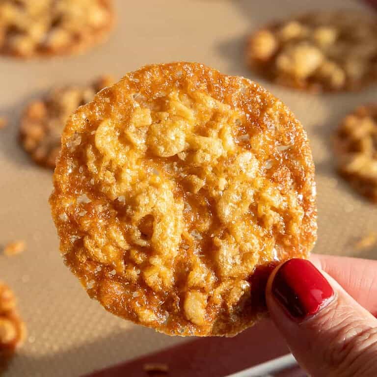image of an oatmeal lace cookie being held up in the sunshine to show how perfectly caramelized it is