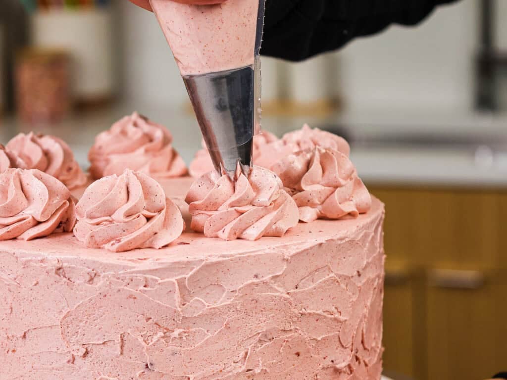 image of a cake that's being frosted with a strawberry swiss meringue buttercream frosting