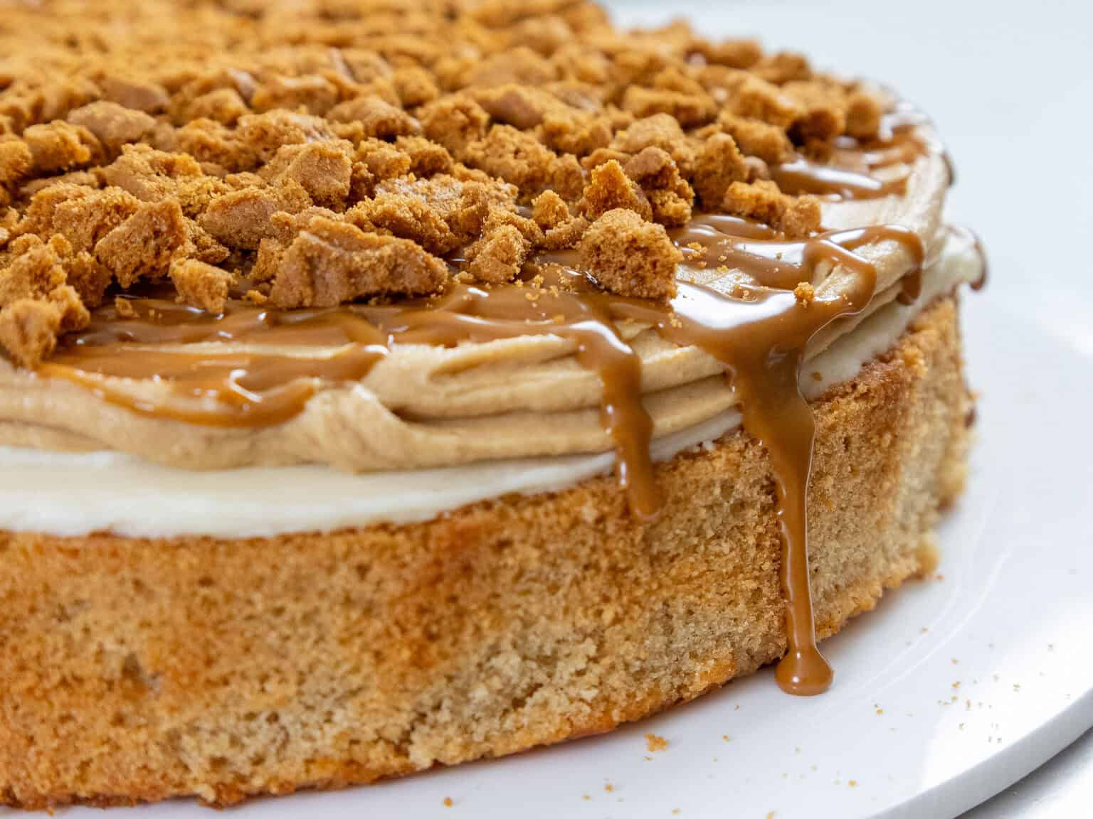 image of a lotus cake being assembled with biscoff cake layers, cookie butter frosting, and a cookie butter drizzle