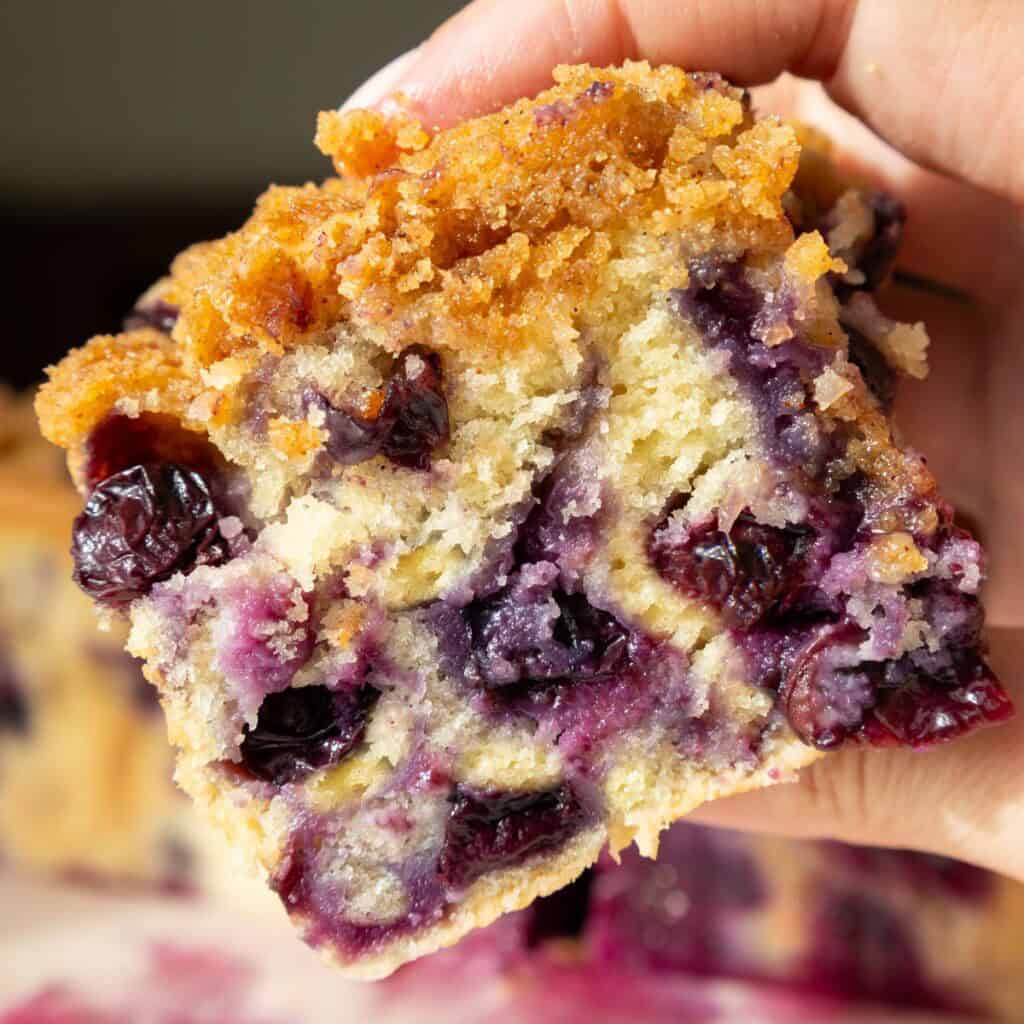 image of a slice of blueberry buttermilk coffee cake that's being held up