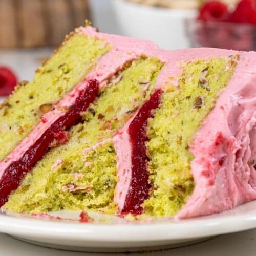 image of a raspberry pistachio cake slice that's been cut into to show it's filling and tender cake layers