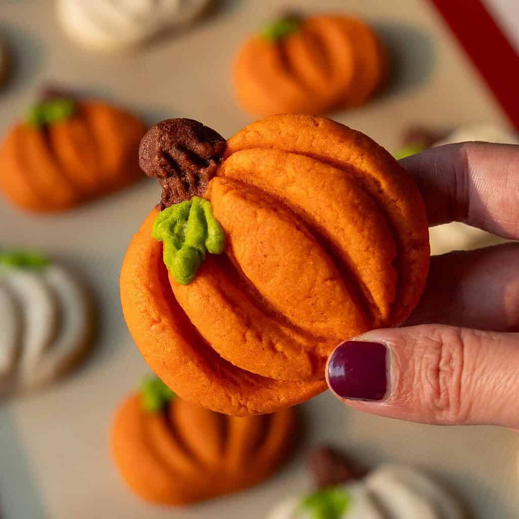 image of pumpkin-shaped cookies that have been baked and are being held up