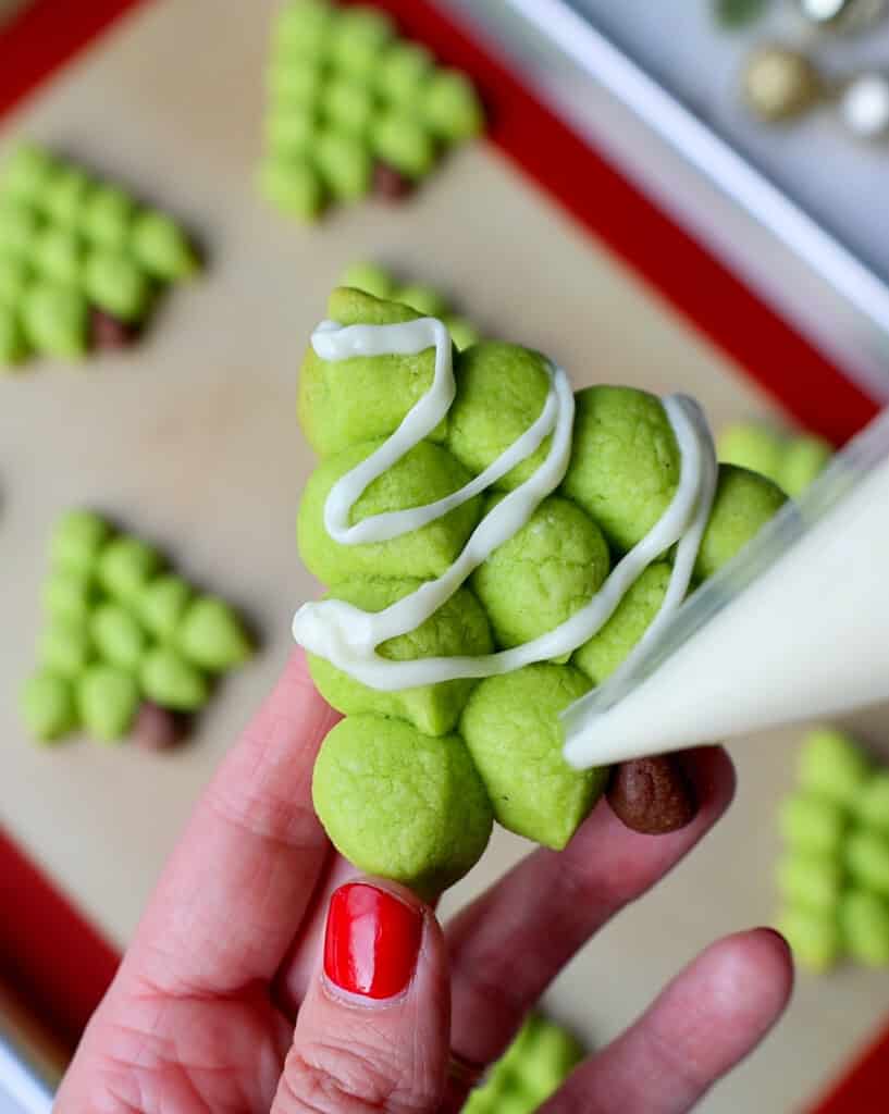 drizzling white chocolate over a christmas tree cookie