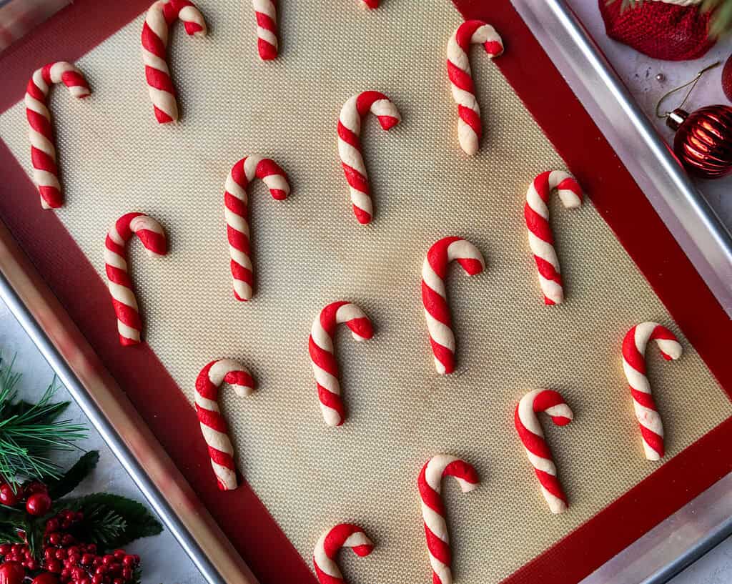 image of candy cane shaped and flavored cookies that have been baked and are cooling on a baking tray