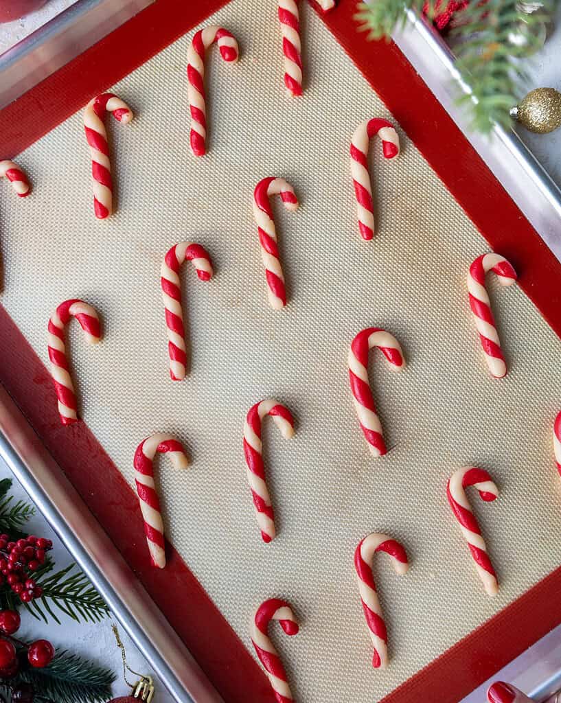 image of candy cane shaped and flavored cookies that have been baked and are cooling on a baking tray