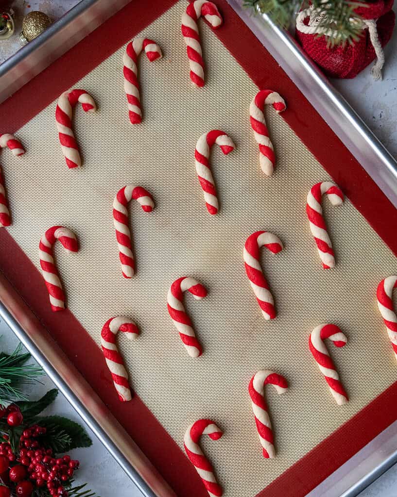 image of candy cane shaped and flavored cookies that have been baked and are cooling on a baking tray