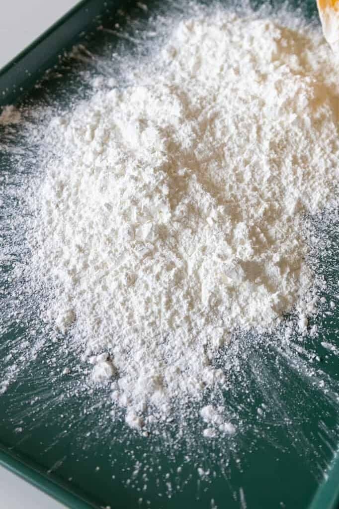 image of cornstarch being poured onto a large baking sheet to make marshmallows