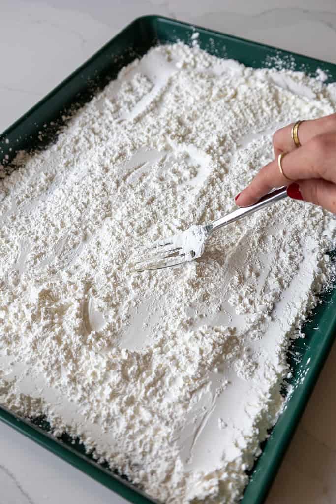 smoothing cornstarch out on a baking sheet to make marshmallows