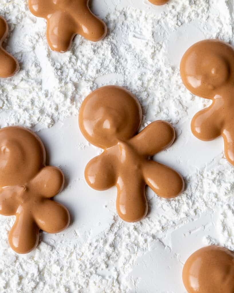 image of a gingerbread man marshmallow being piped onto a baking tray coated in cornstarch