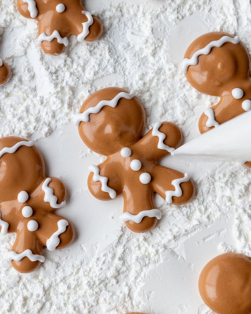 image of white lines being piped onto gingerbread men marshmallows