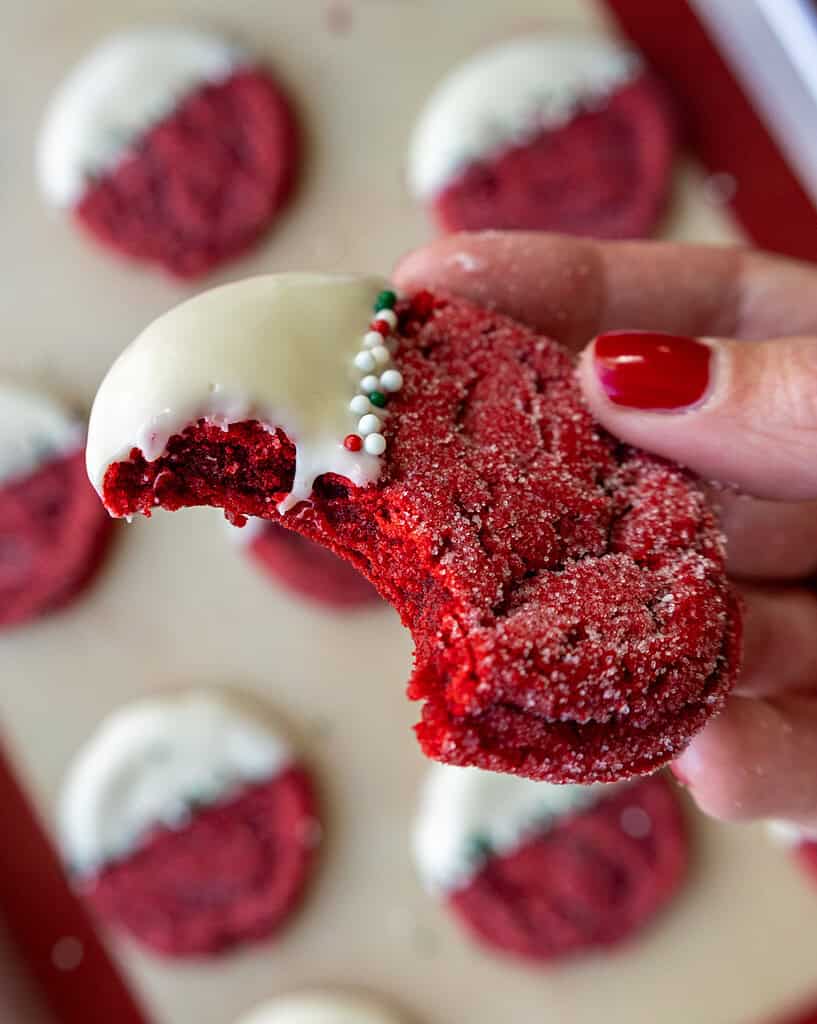 image of red velvet sugar cookies that have bitten into to show how perfectly chewy they are