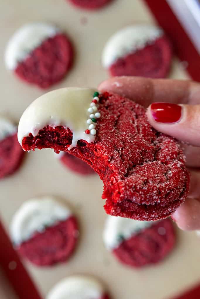 image of red velvet sugar cookies that have bitten into to show how perfectly chewy they are