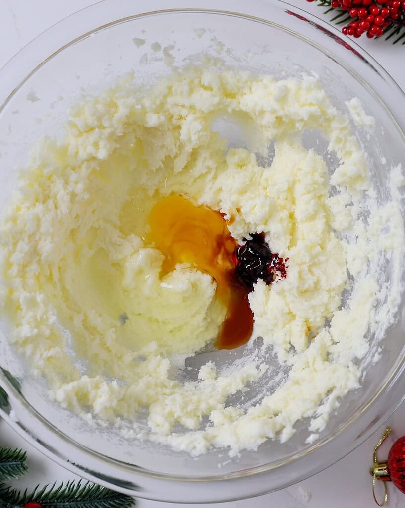 image of an egg and red gel food coloring being mixed into creamed sugar and butter