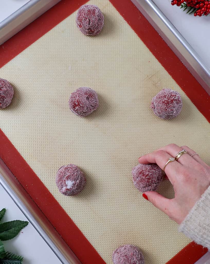 image of red velvet sugar cookies being placed on a baking sheet to be baked
