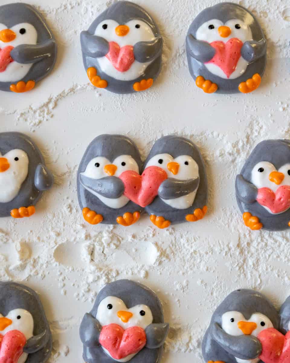 image of penguin marshmallows that have been piped on a baking sheet