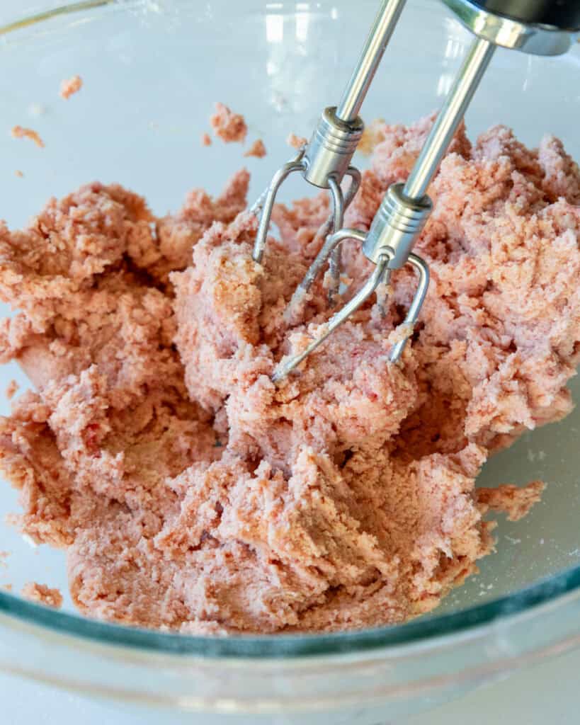 image of strawberry shortbread dough that's been mixed together in a glass bowl 