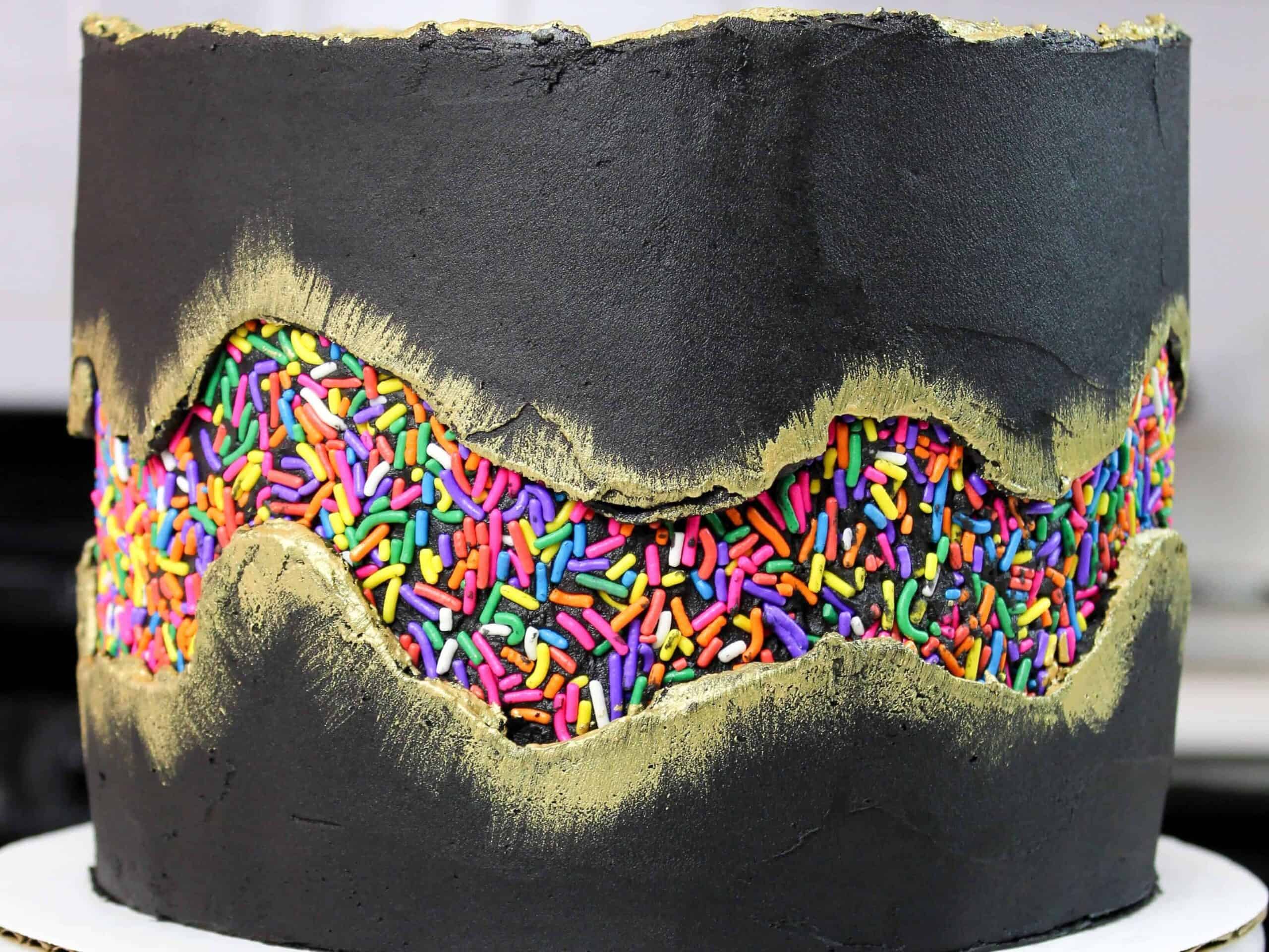 image of sprinkle fault line cake, frosted with black buttercream