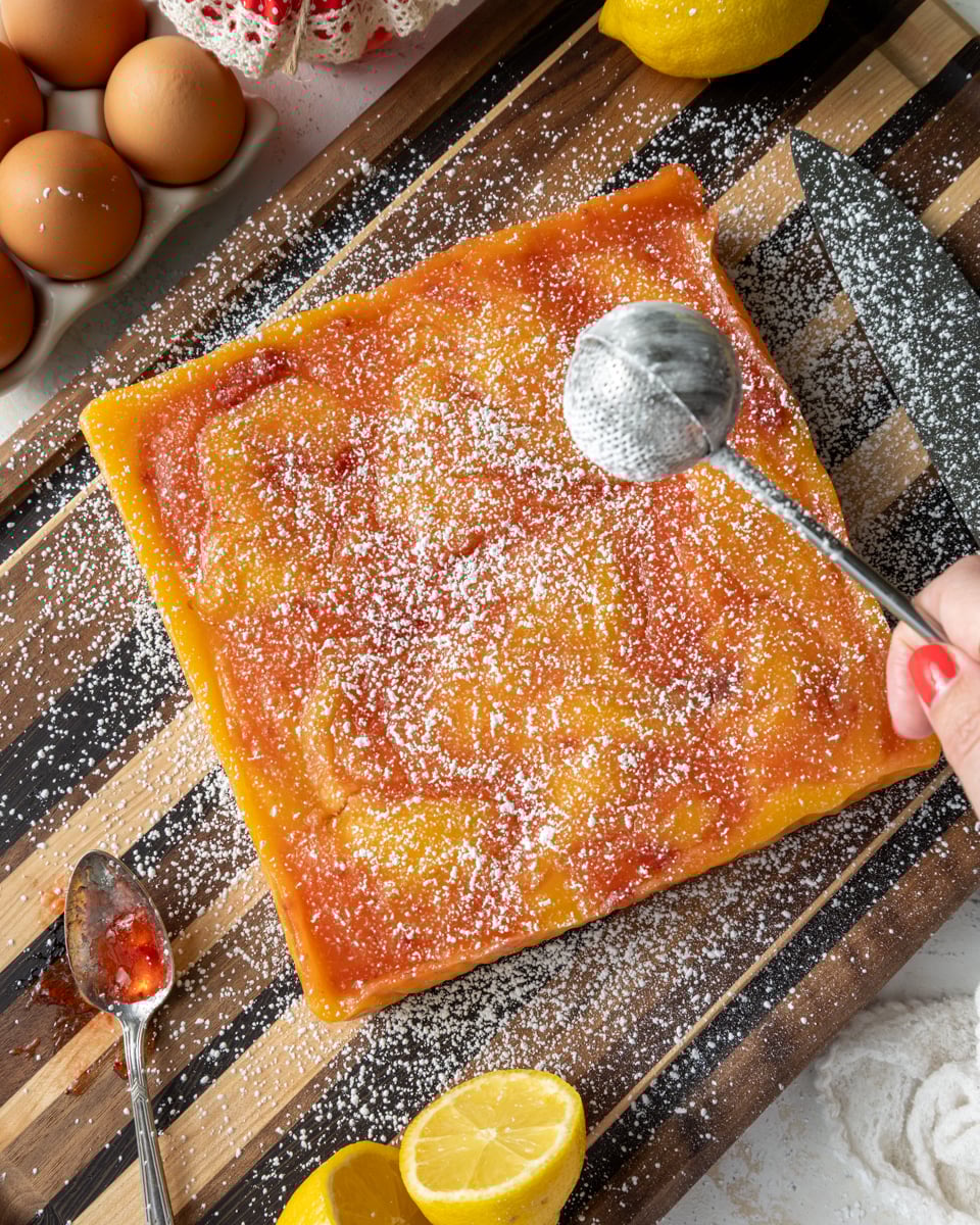 image of strawberry lemon bars that are being dusted with powdered sugar