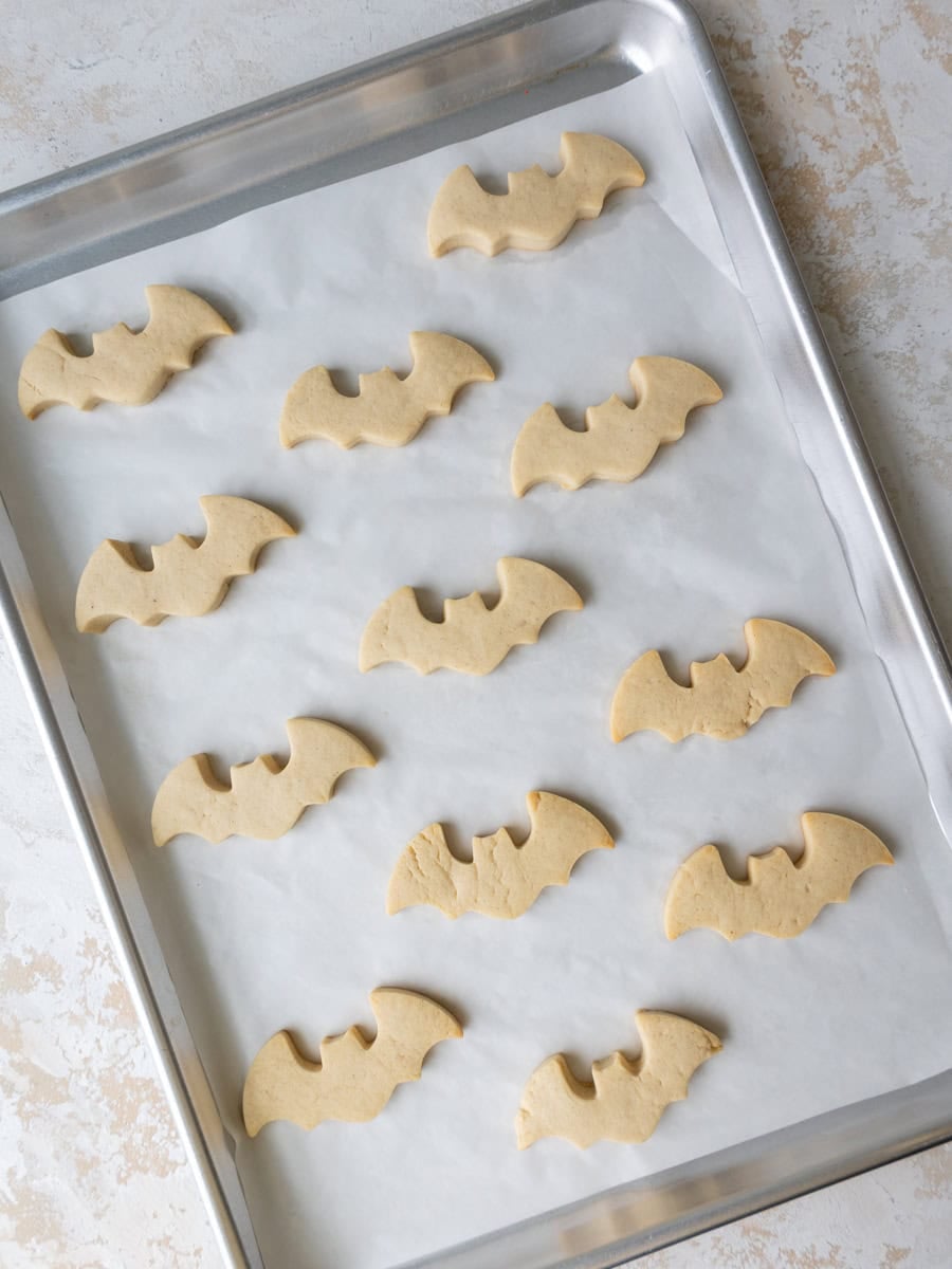 image of baked, bat shaped cookies that are cooling on metal baking sheet before being decorated with royal icing