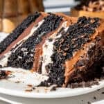 image of an Oreo fudge cake slice that's been cut into on a plate to show its Oreo frosting and fudge filling