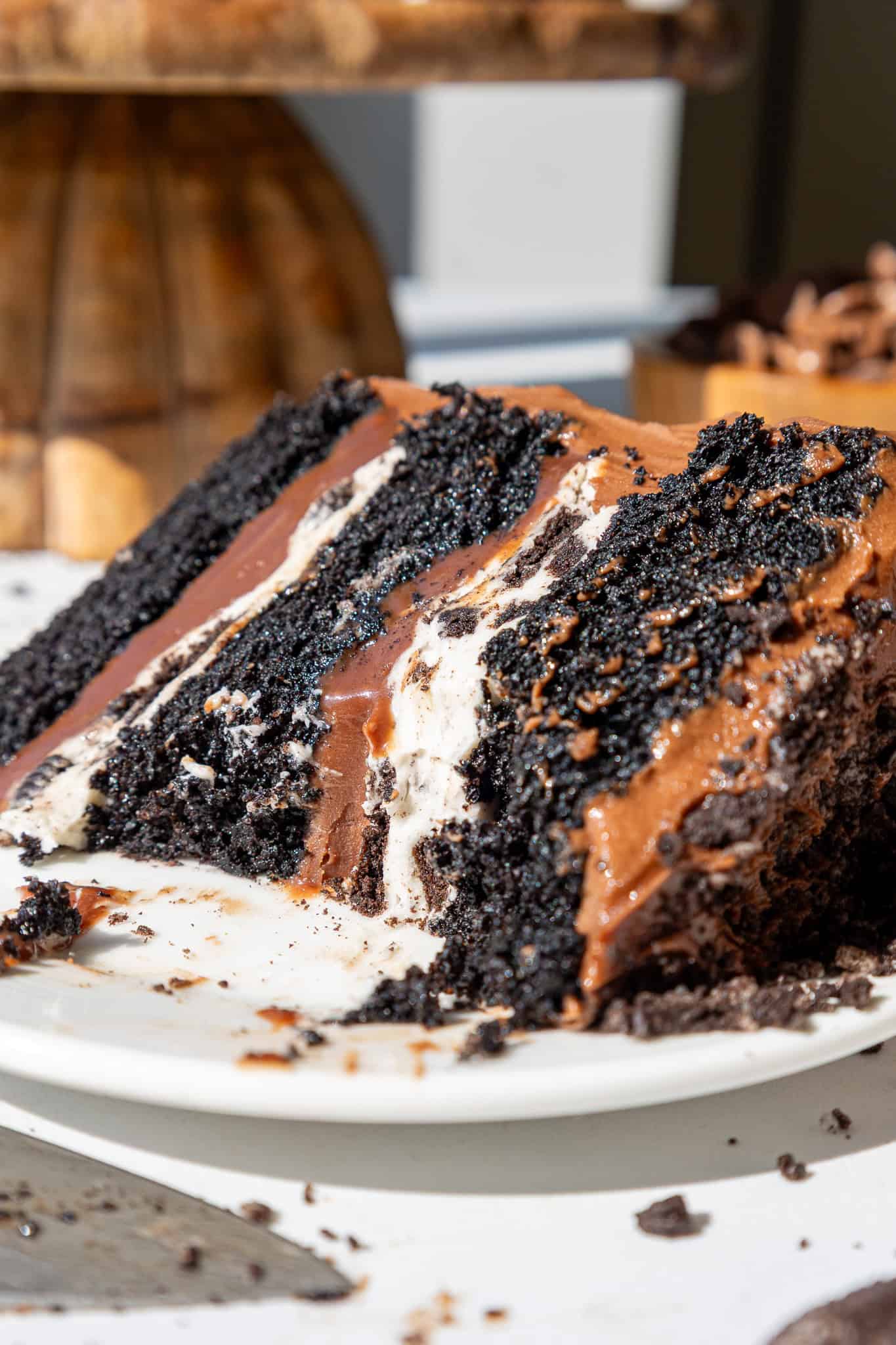 image of an Oreo fudge cake slice that's been cut into on a plate to show its Oreo frosting and fudge filling
