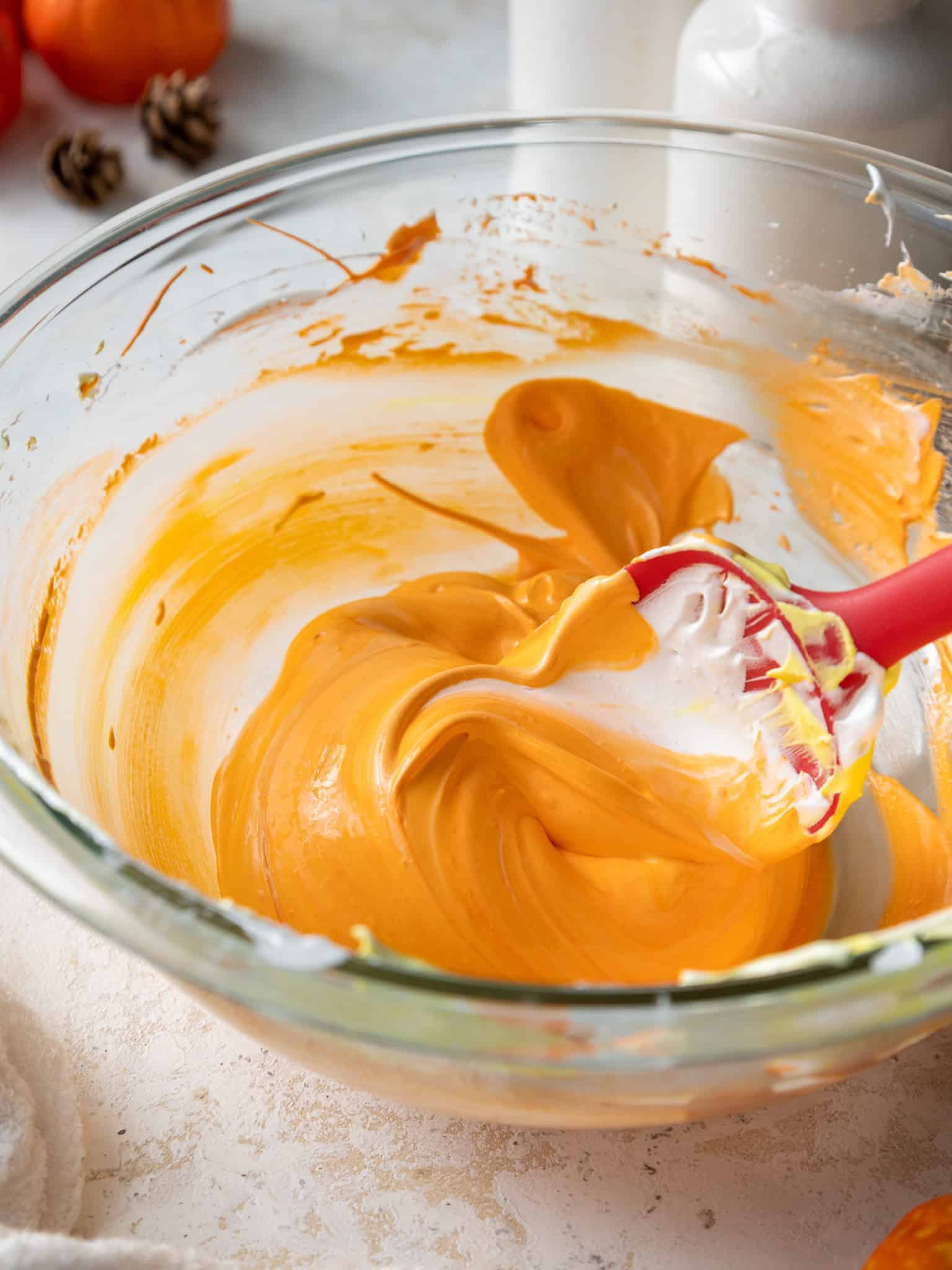 image of orange french meringue being mixed in a glass bowl
