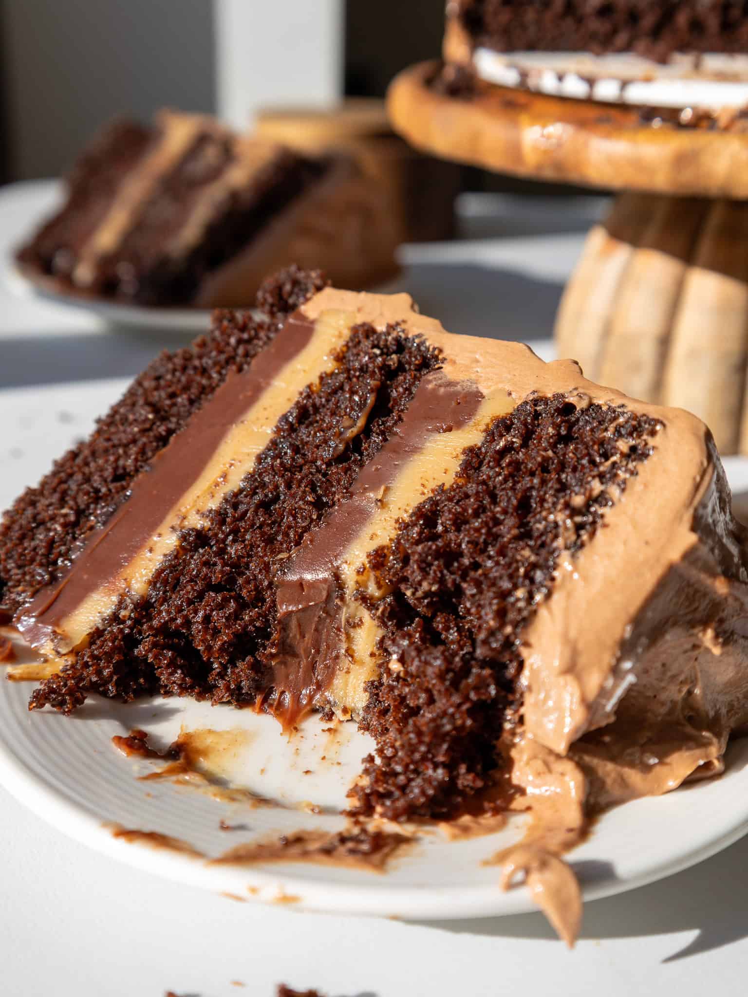 image of a slice of peanut butter fudge cake that's been cut into to show it's peanut butter and chocolate ganache filling