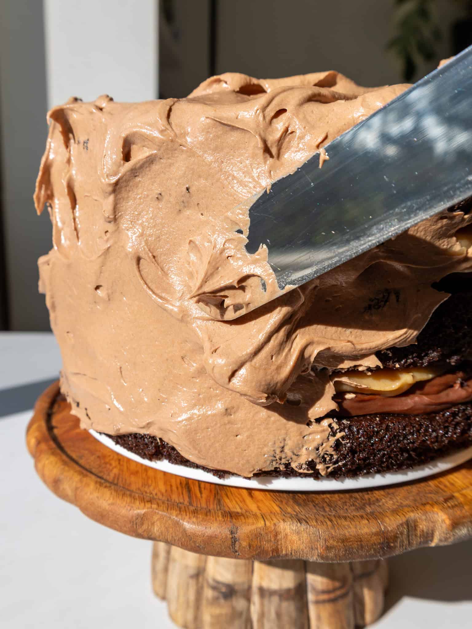 image of a peanut butter fudge cake being frosted with whipped chocolate peanut butter ganache