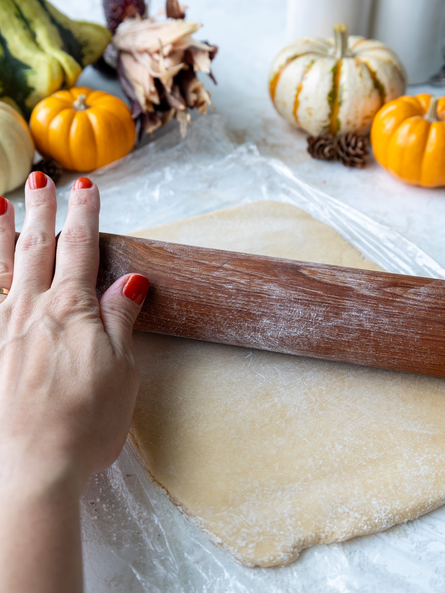 image of cream cheese cookie dough rolled out on plastic wrap before cutting turkey cookies