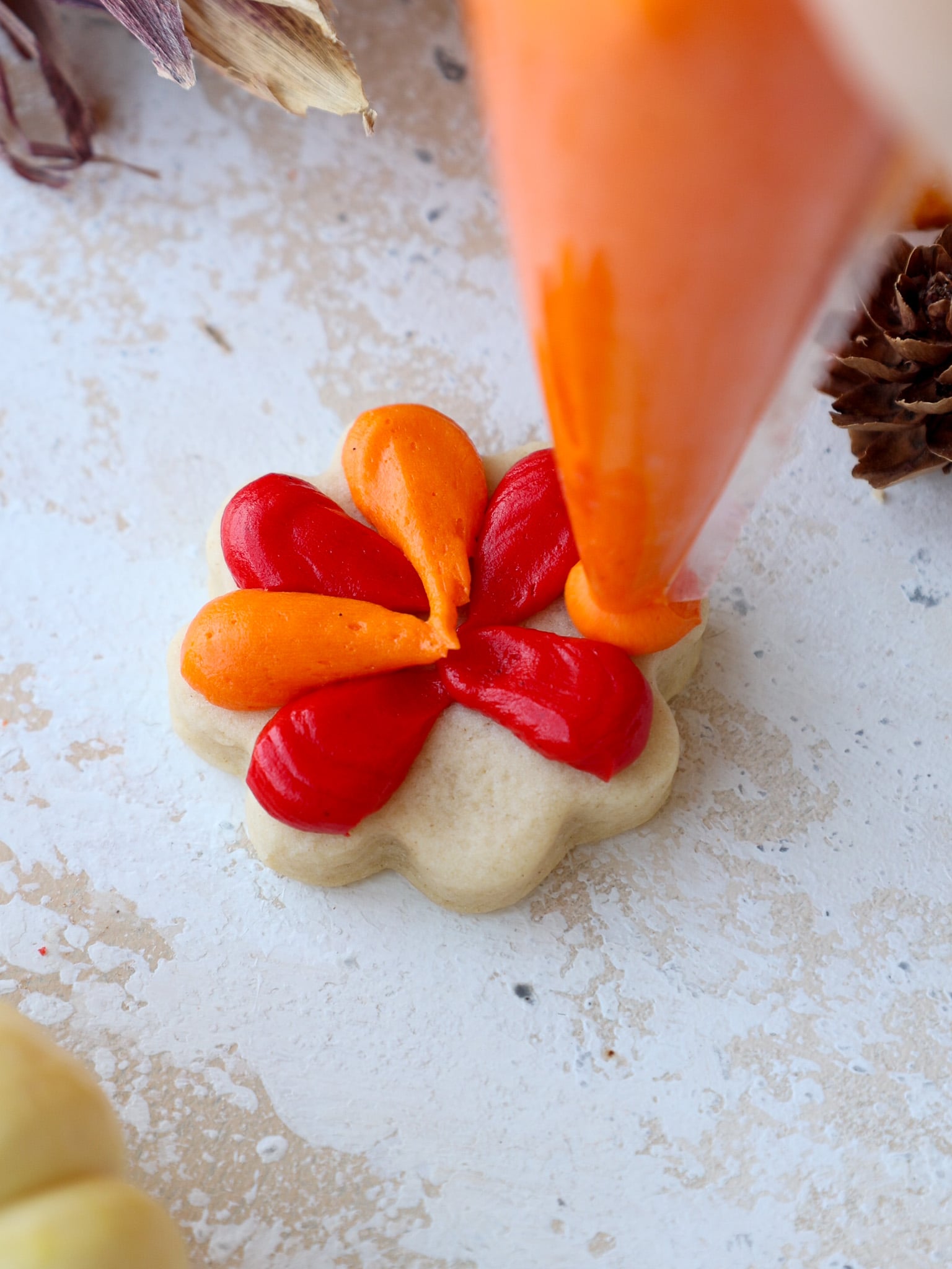 image of red and orange buttercream feathers being piped onto turkey cookies