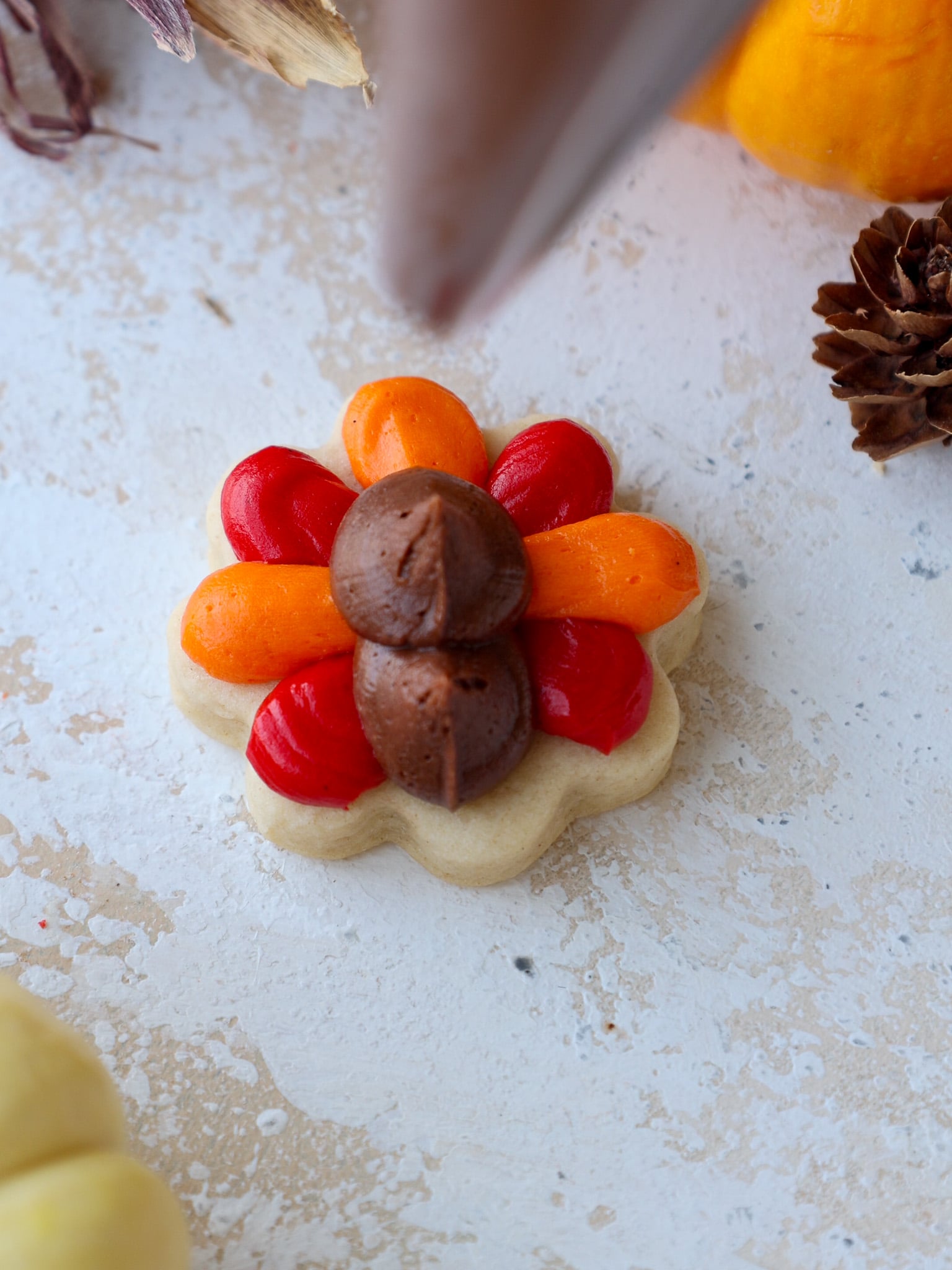 image of brown buttercream bodies and heads being piped onto turkey cookies