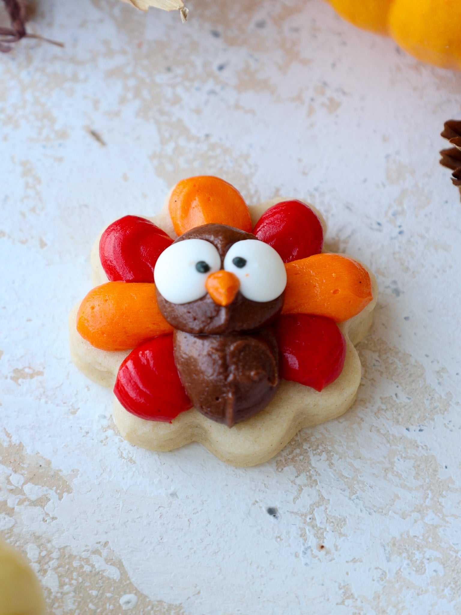 image of buttercream turkey cookies being decorated with candy eyes, beaks, and feet