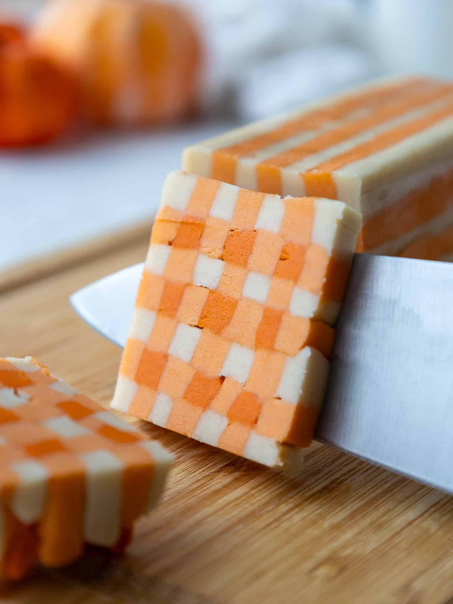 image of a gingham shortbread cookie dough log being cut into slices