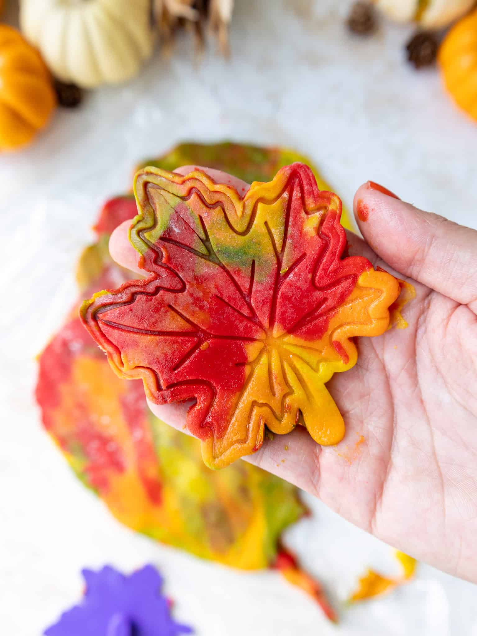 image of a maple leaf cookie being cut from marbled cookie dough