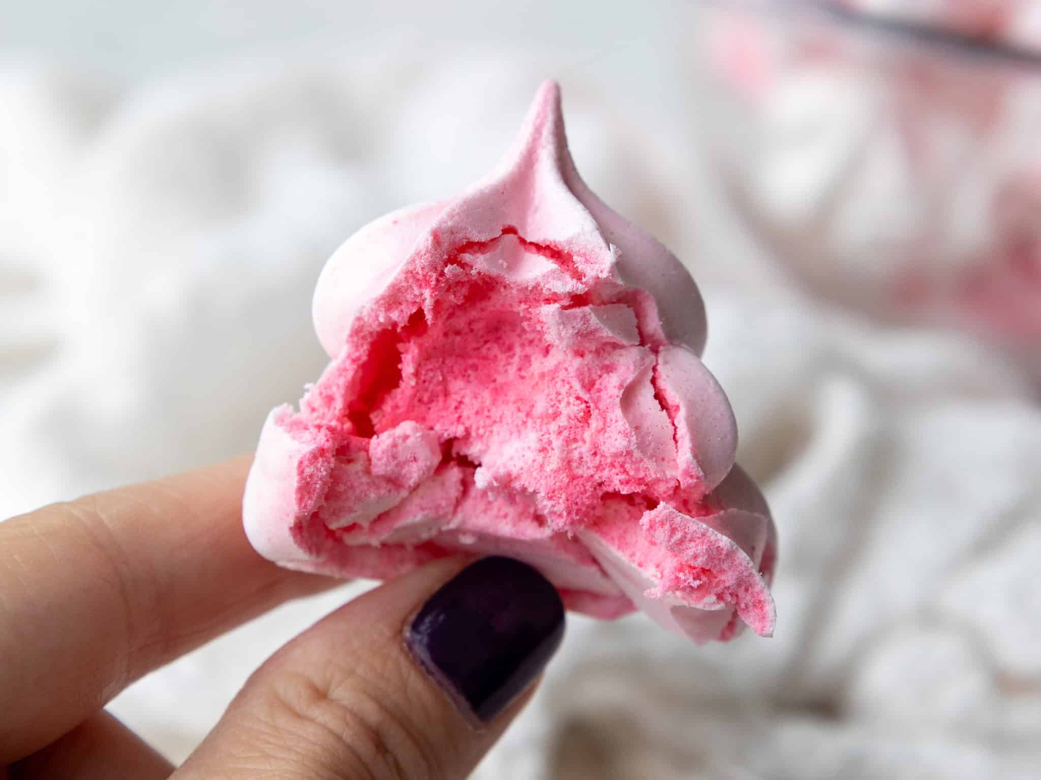 image of a meringue cookie that's been bitten into to show its crunchy exterior and soft chewy interior